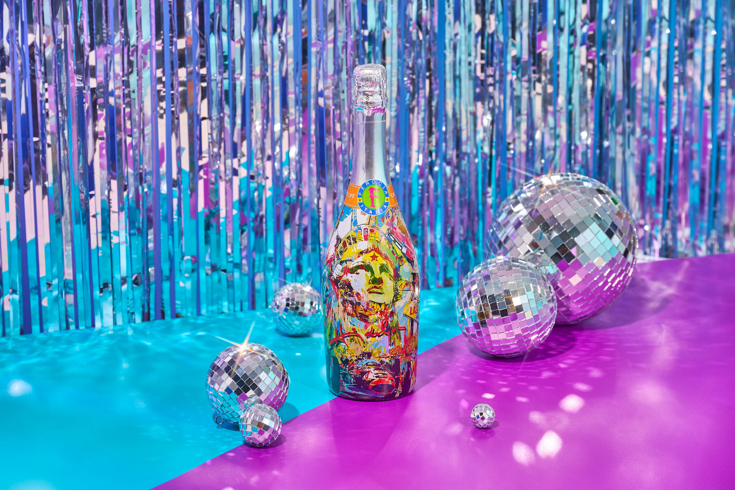 Bottle of champagne with disco ball decorations against a shiny curtain background.